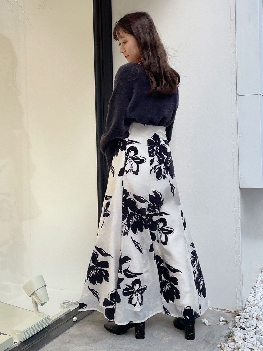 ブラウン系のハンドバッグ、ブラック系のブーツ、ホワイト系のスカートを着用したレディースの秋コーディネートの6枚目の写真