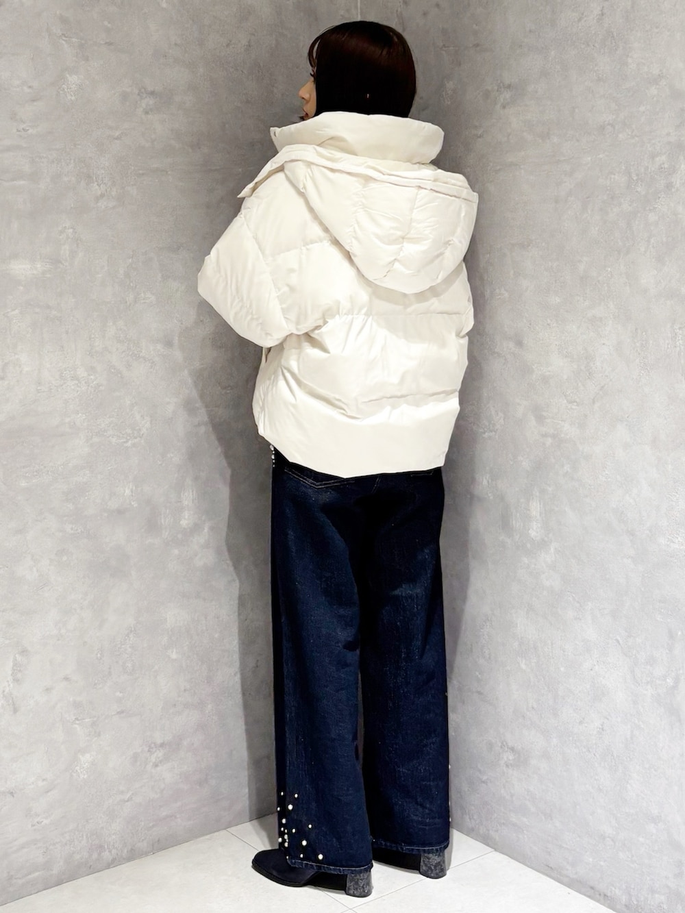 ブルー系のデニムパンツ、ホワイト系のダウンジャケット/コート、ベージュ系のニット/セーターを着用したレディースの秋コーディネートの3枚目の写真