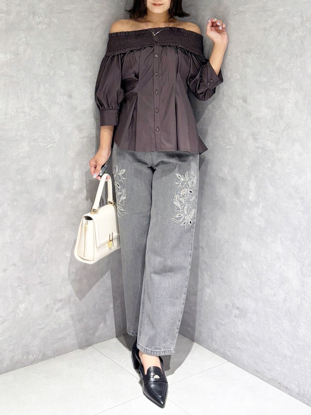 ホワイト系のハンドバッグ、ブラック系のパンプス、グレー系のデニムパンツを着用したレディースの夏コーディネートの7枚目の写真