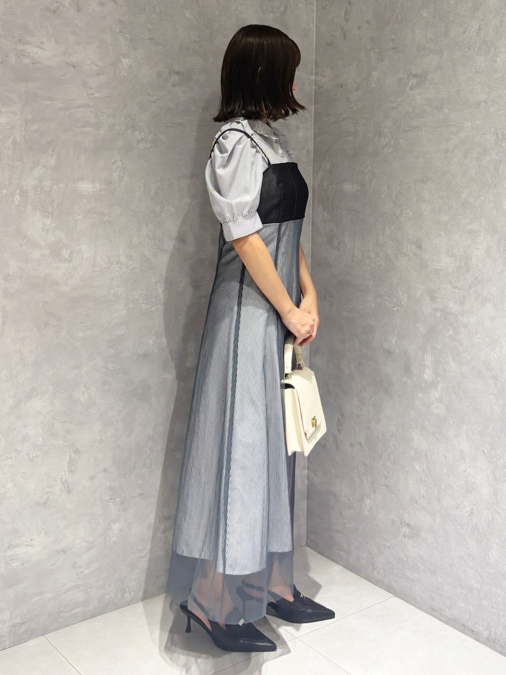 ブラック系のパンプス、ホワイト系のハンドバッグ、ブルー系のワンピースを着用したレディースの秋コーディネートの5枚目の写真