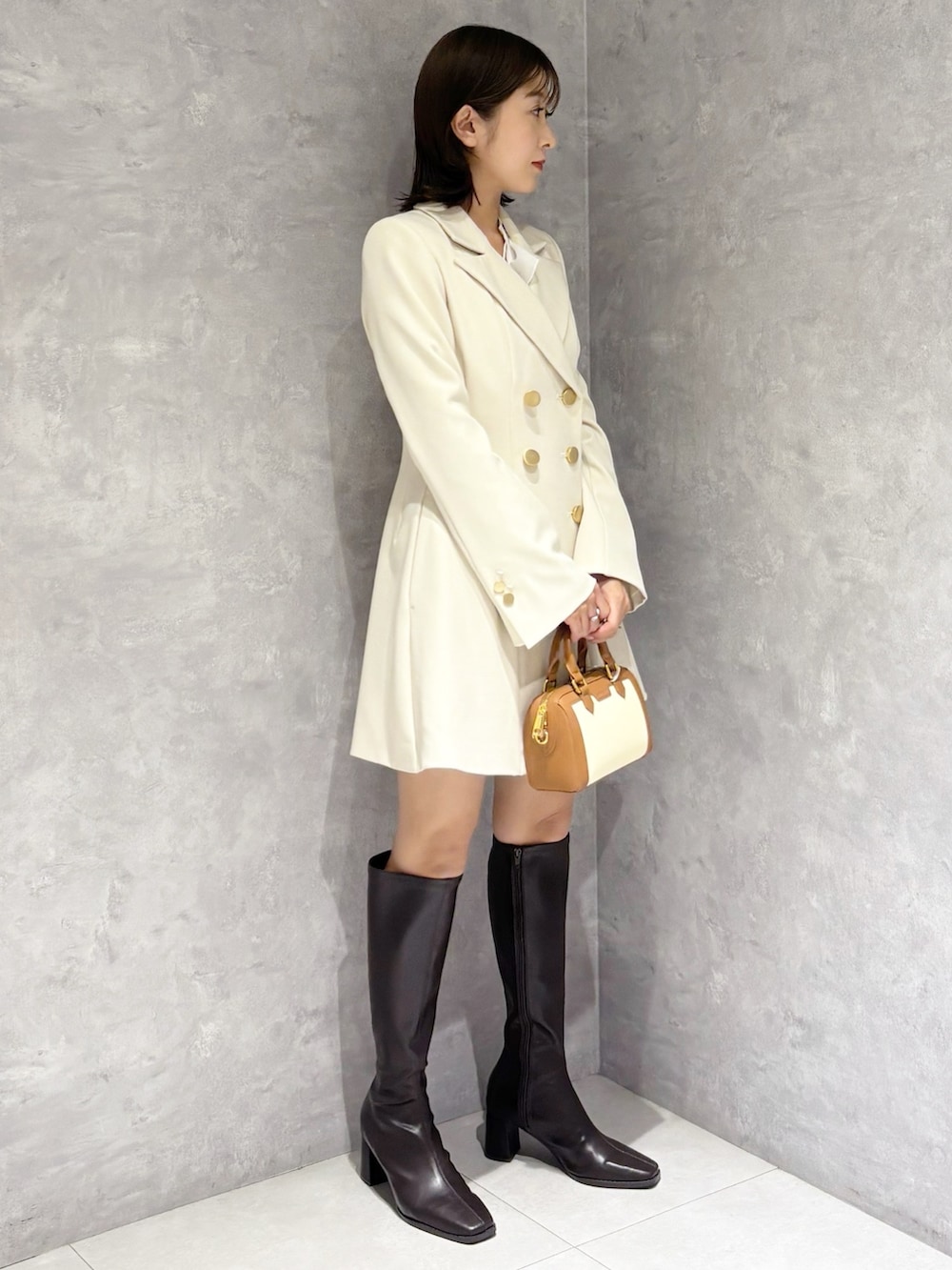 ホワイト系のワンピース、ホワイト系のシャツ/ブラウス、ブラウン系のハンドバッグを着用したレディースの春コーディネートの2枚目の写真
