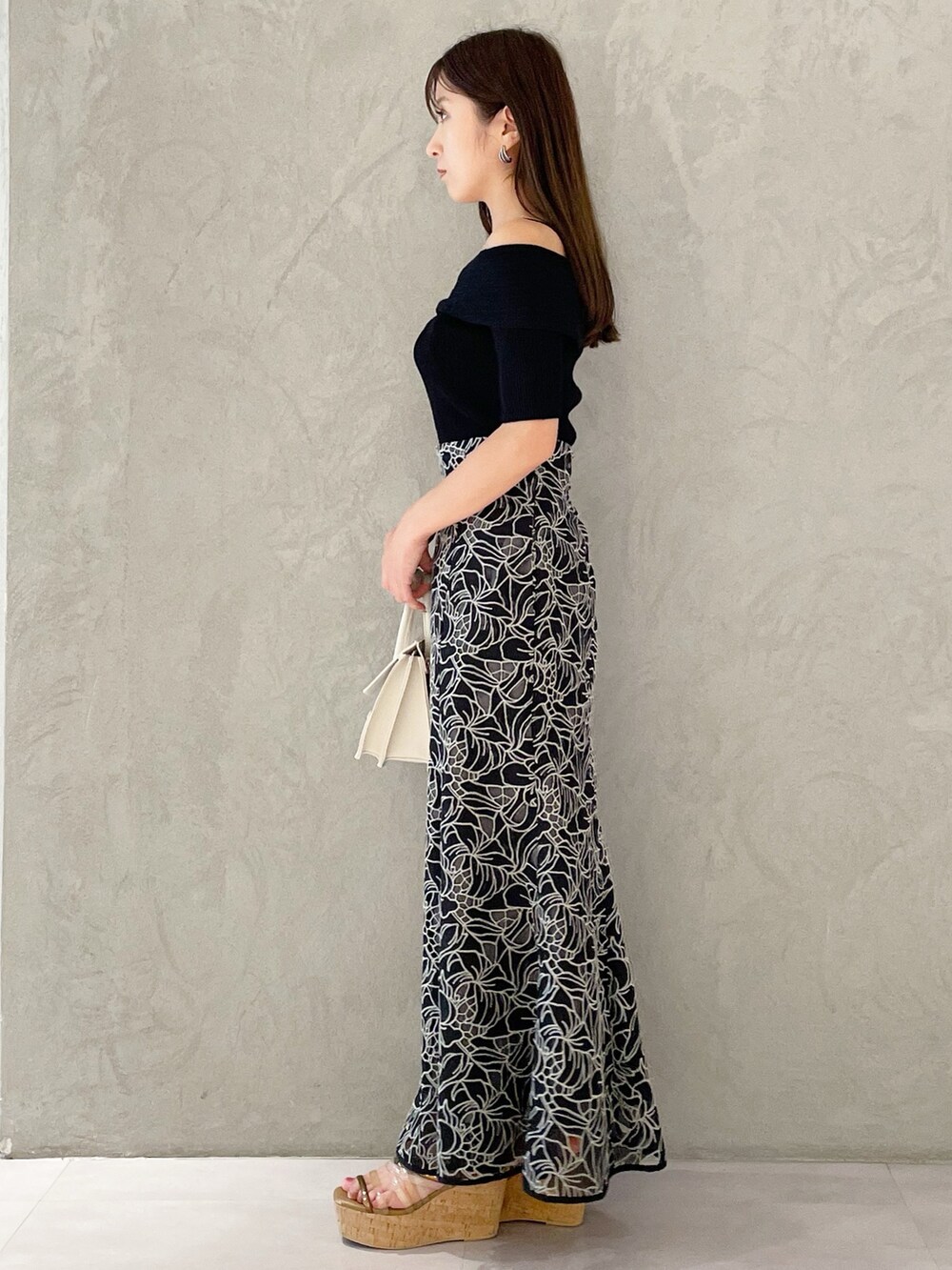 ブラック系のスカート、ブラウン系のサンダル、ベージュ系のショルダーバッグを着用したレディースの夏コーディネートの2枚目の写真