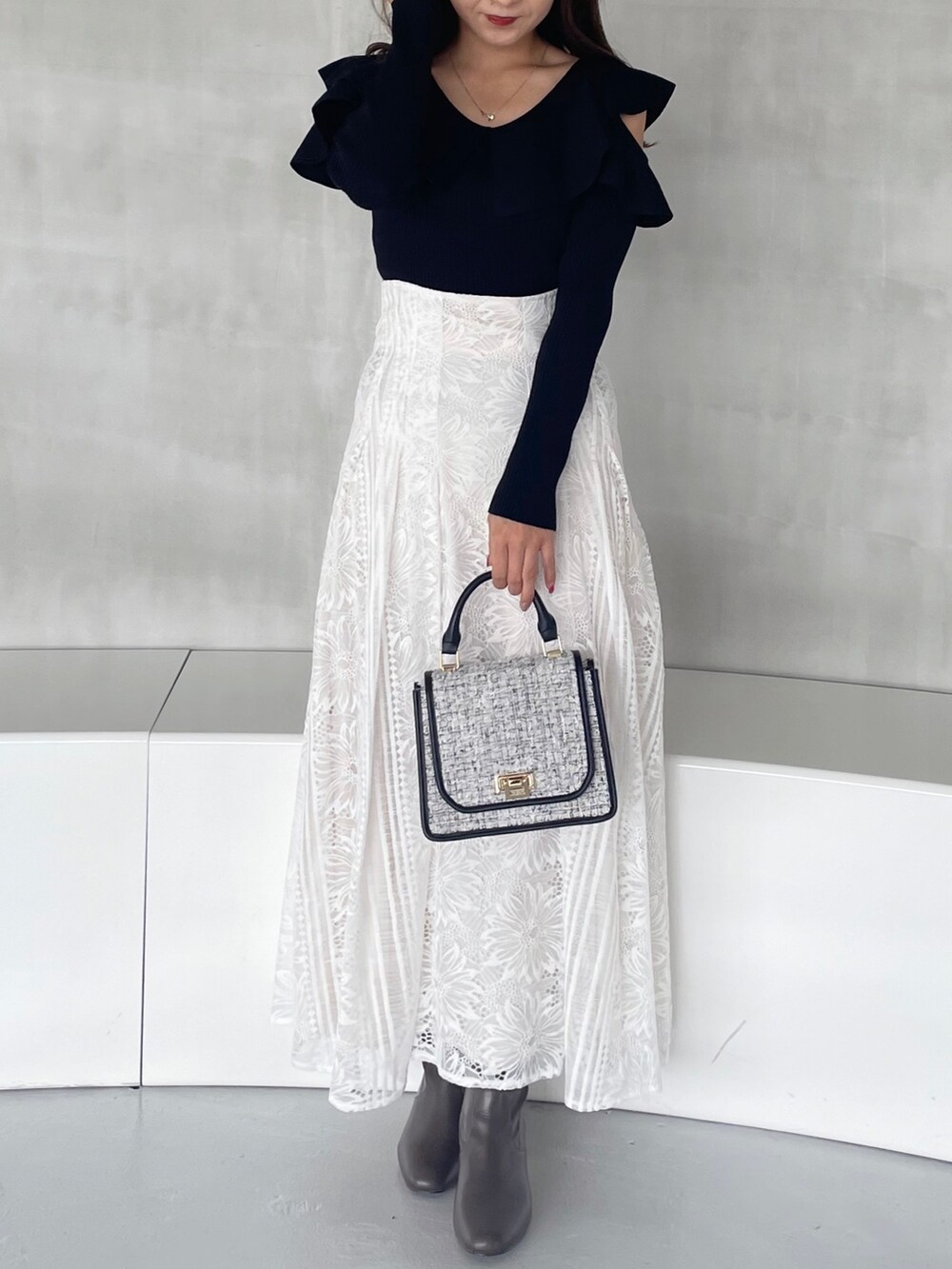 ホワイト系のスカート、ブラック系のショルダーバッグ、ブラウン系のブーツを着用したレディースの秋コーディネートの5枚目の写真