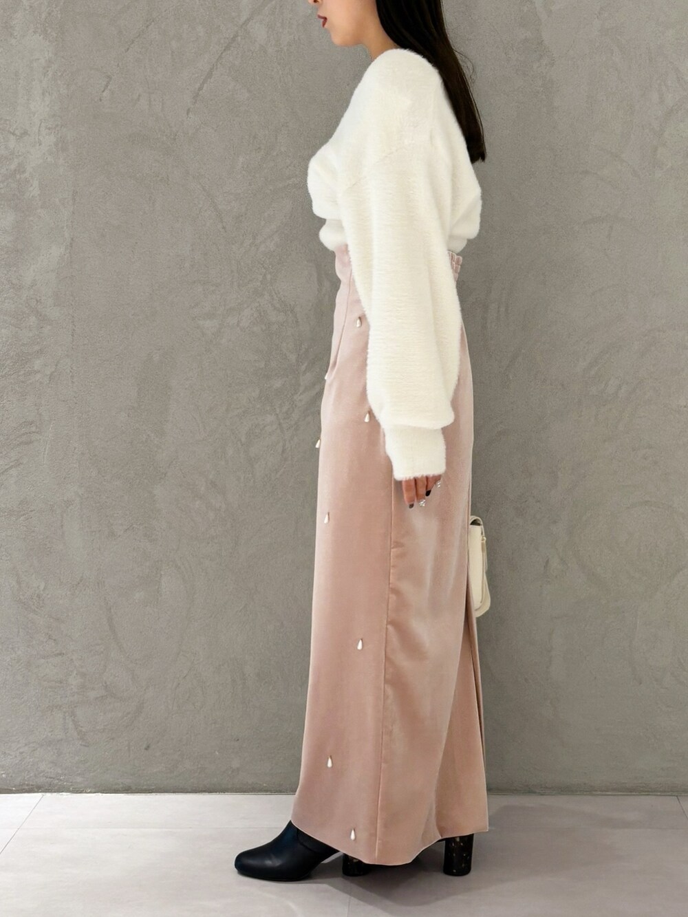 ピンク系のスカート、ブラック系のブーツ、ホワイト系のニット/セーターを着用したレディースの冬コーディネートの2枚目の写真