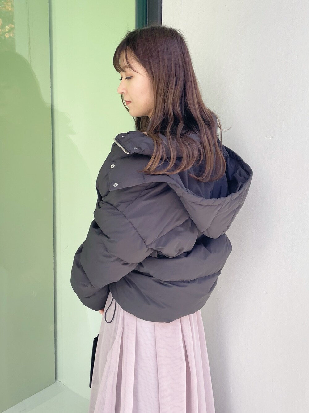 グレー系のワンピース、ブラック系のダウンジャケット/コート、ブラック系のハンドバッグを着用したレディースの冬コーディネートの2枚目の写真