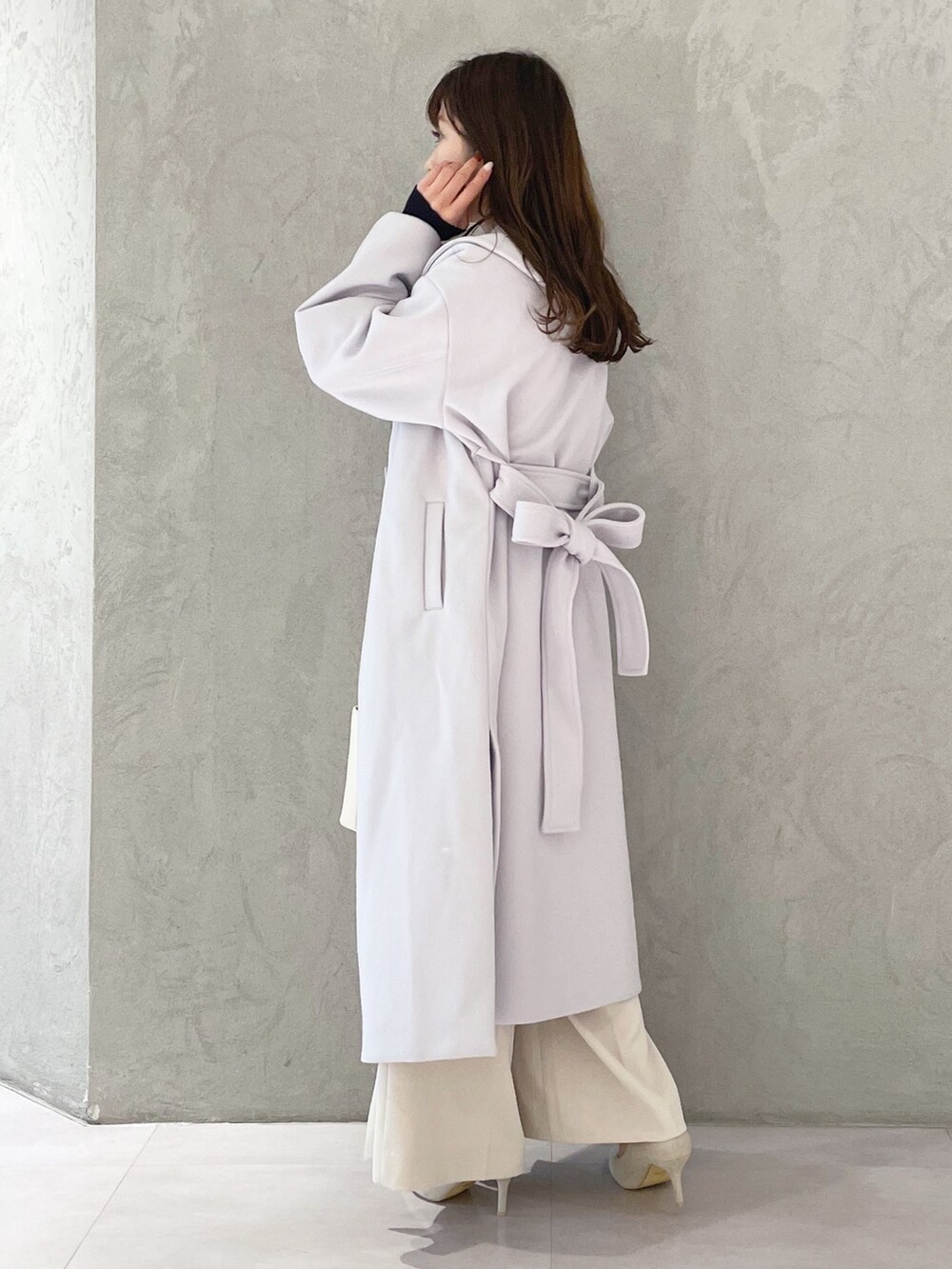 ホワイト系のハンドバッグ、ホワイト系のパンプス、ブルー系のニット/セーターを着用したレディースの秋コーディネートの3枚目の写真