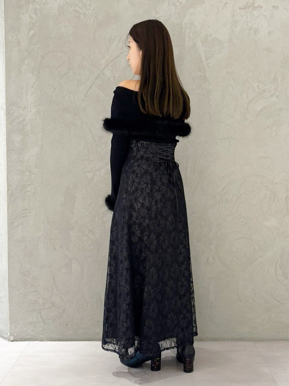 ブラック系のスカート、ブラック系のブーツ、ブラック系のショルダーバッグを着用したレディースの冬コーディネートの6枚目の写真