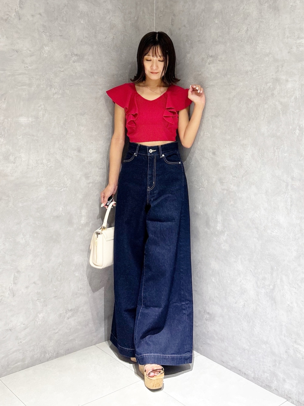 ブルー系のデニムパンツ、ブラウン系のサンダル、ホワイト系のハンドバッグを着用したレディースの夏コーディネートの6枚目の写真