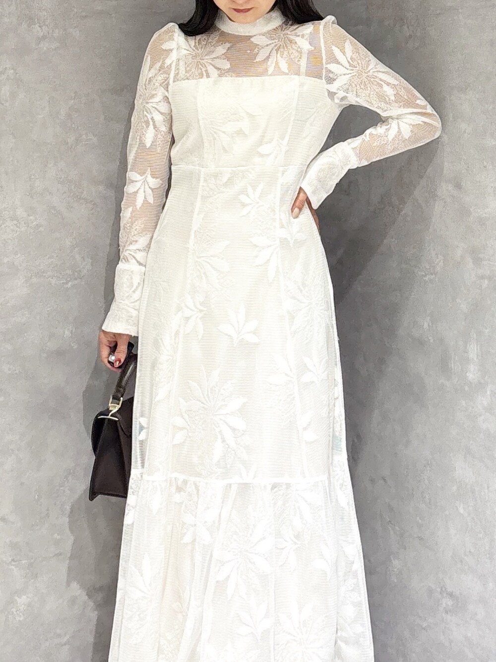 ホワイト系のワンピース、ブラウン系のハンドバッグ、ブラウン系のブーツを着用したレディースの冬コーディネートの6枚目の写真