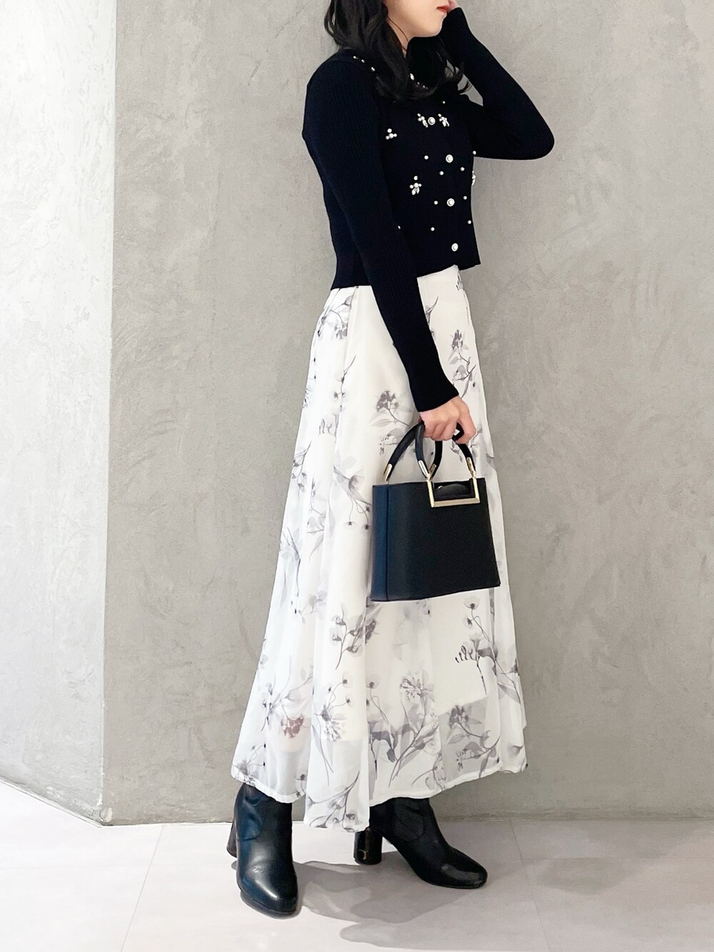 ブラック系のハンドバッグ、ブラック系のブーツ、ホワイト系のスカートを着用したレディースの冬コーディネートの4枚目の写真