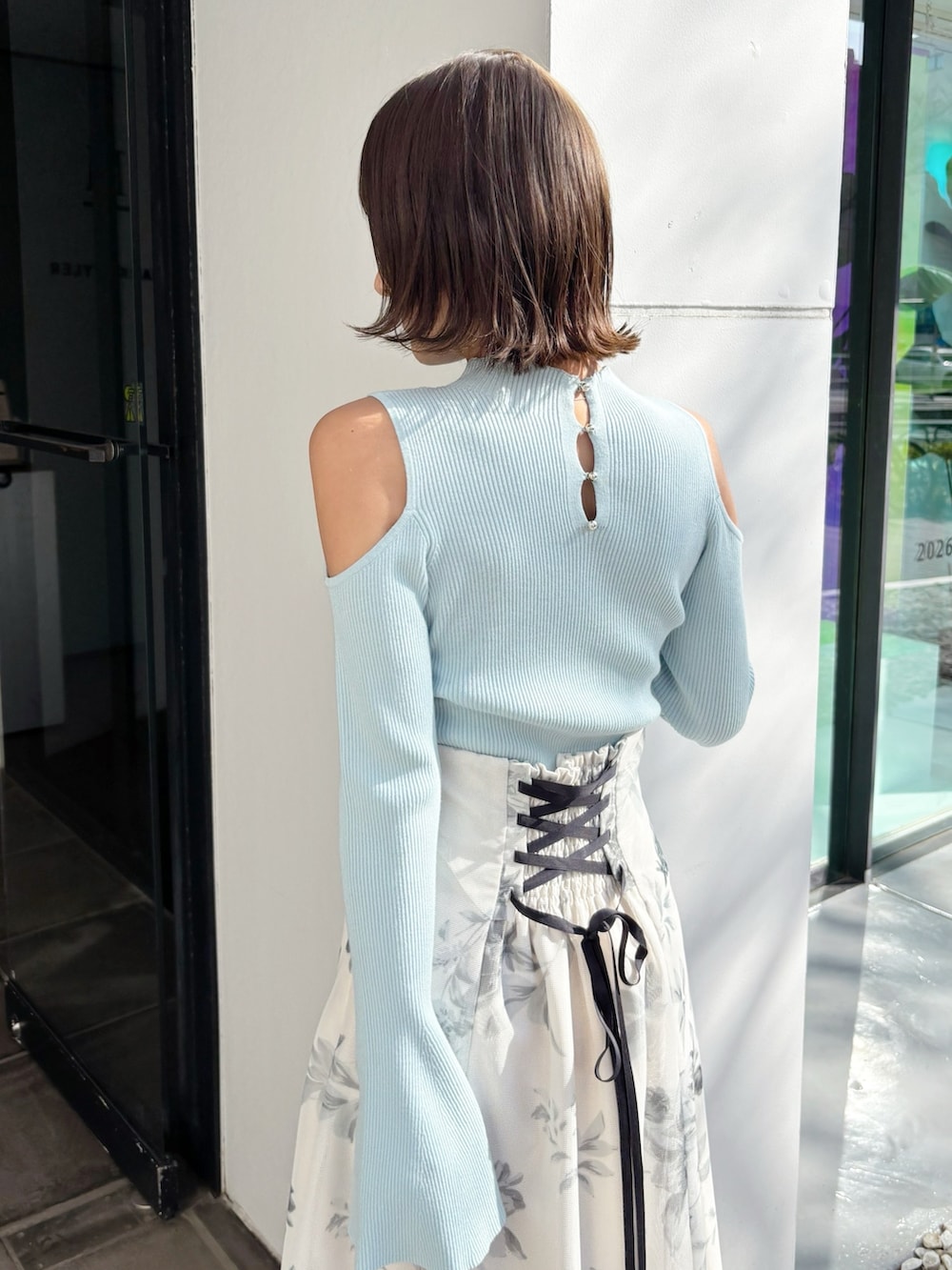 ホワイト系のスカート、グリーン系のニット/セーター、ホワイト系のパンプスを着用したレディースの春コーディネートの3枚目の写真