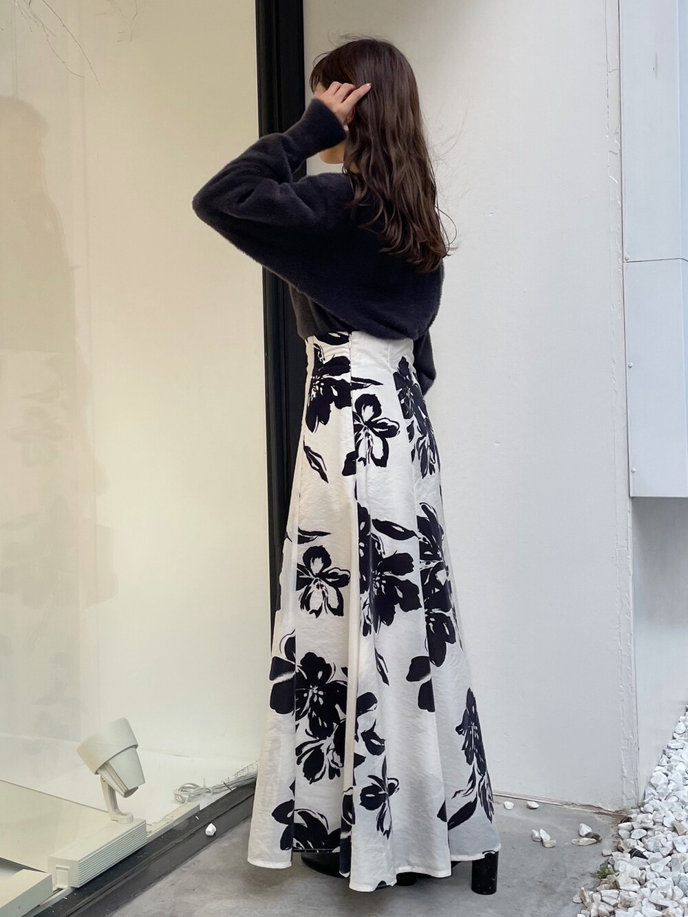 ブラウン系のハンドバッグ、ブラック系のブーツ、ホワイト系のスカートを着用したレディースの秋コーディネートの3枚目の写真