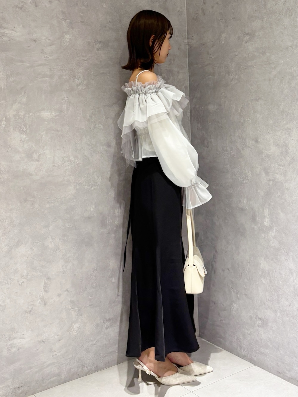 ブラック系のスカート、ホワイト系のパンプス、グリーン系のシャツ/ブラウスを着用したレディースの春コーディネートの2枚目の写真