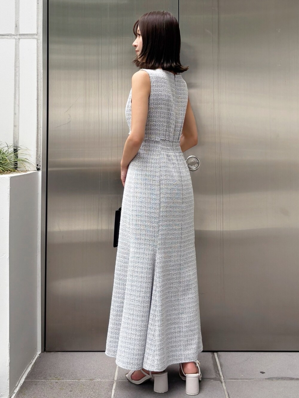 グレー系のワンピース、ホワイト系のサンダル、ブラック系のハンドバッグを着用したレディースの夏コーディネートの3枚目の写真