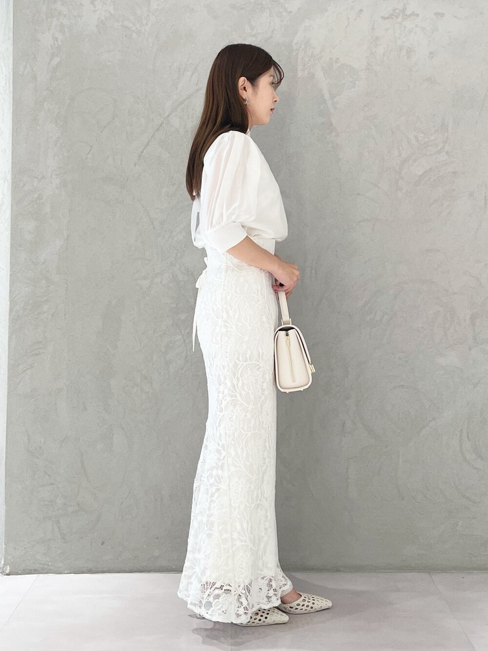 ホワイト系のスカート、ホワイト系のショルダーバッグ、ホワイト系のパンプスを着用したレディースの春コーディネートの3枚目の写真