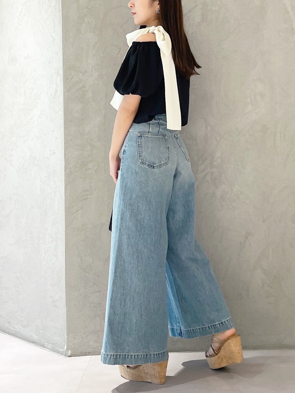 ブラウン系のサンダル、ブラック系のハンドバッグ、ブルー系のデニムパンツを着用したレディースの春コーディネートの5枚目の写真