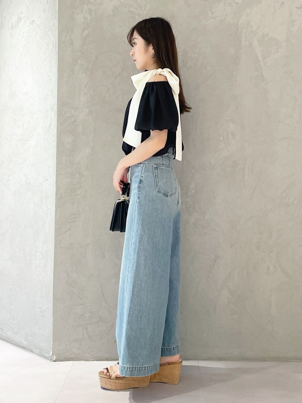 ブラウン系のサンダル、ブラック系のハンドバッグ、ブルー系のデニムパンツを着用したレディースの春コーディネートの2枚目の写真