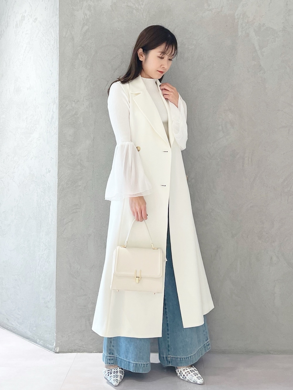 ブルー系のデニムパンツ、ホワイト系のショルダーバッグ、ホワイト系のニット/セーターを着用したレディースの冬コーディネートの3枚目の写真