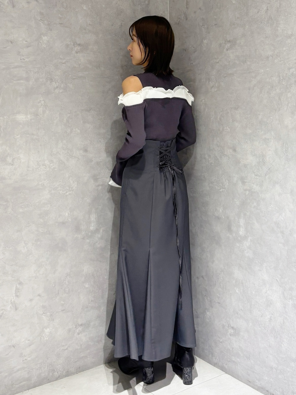 グレー系のスカート、グレー系のニット/セーター、ブラック系のブーツを着用したレディースの冬コーディネートの4枚目の写真