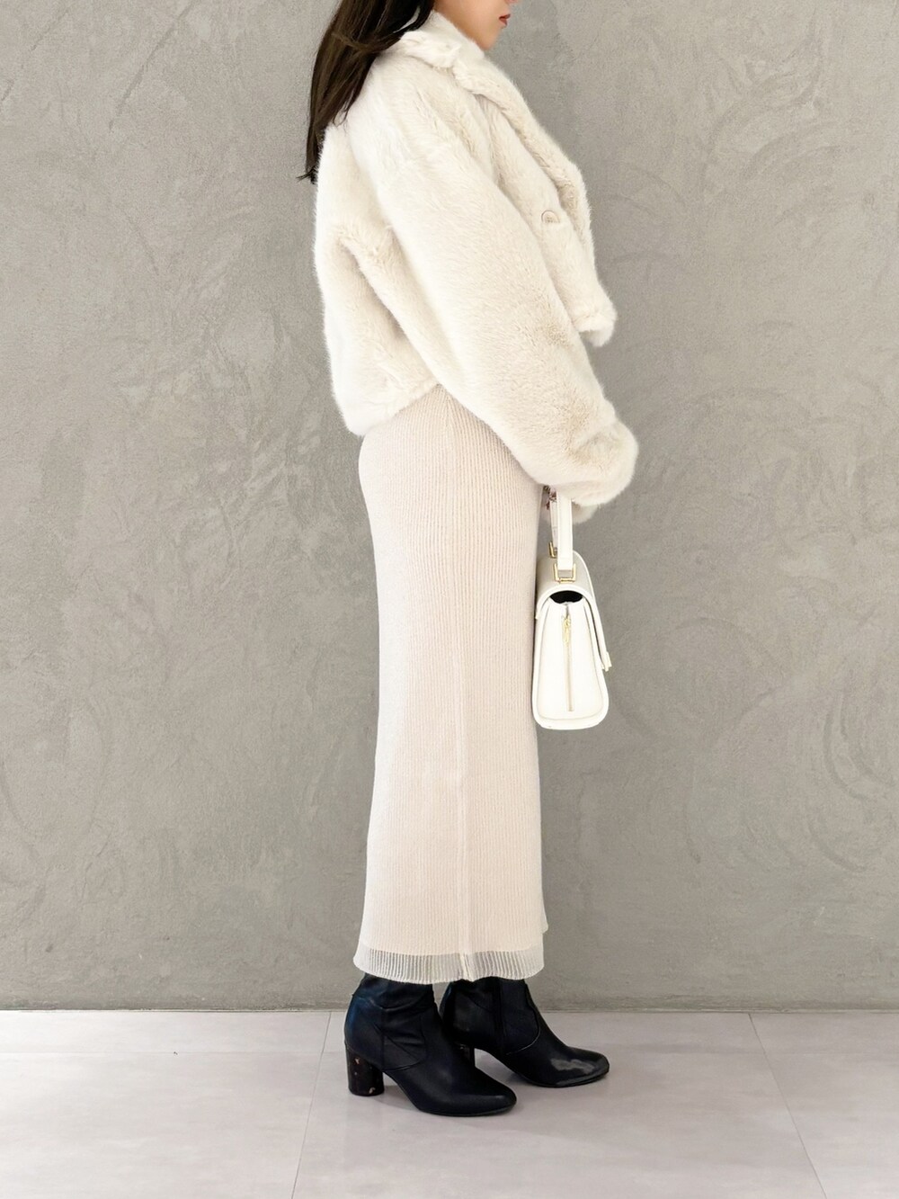 ホワイト系のワンピース、ブラック系のブーツ、ホワイト系のハンドバッグを着用したレディースの冬コーディネートの7枚目の写真