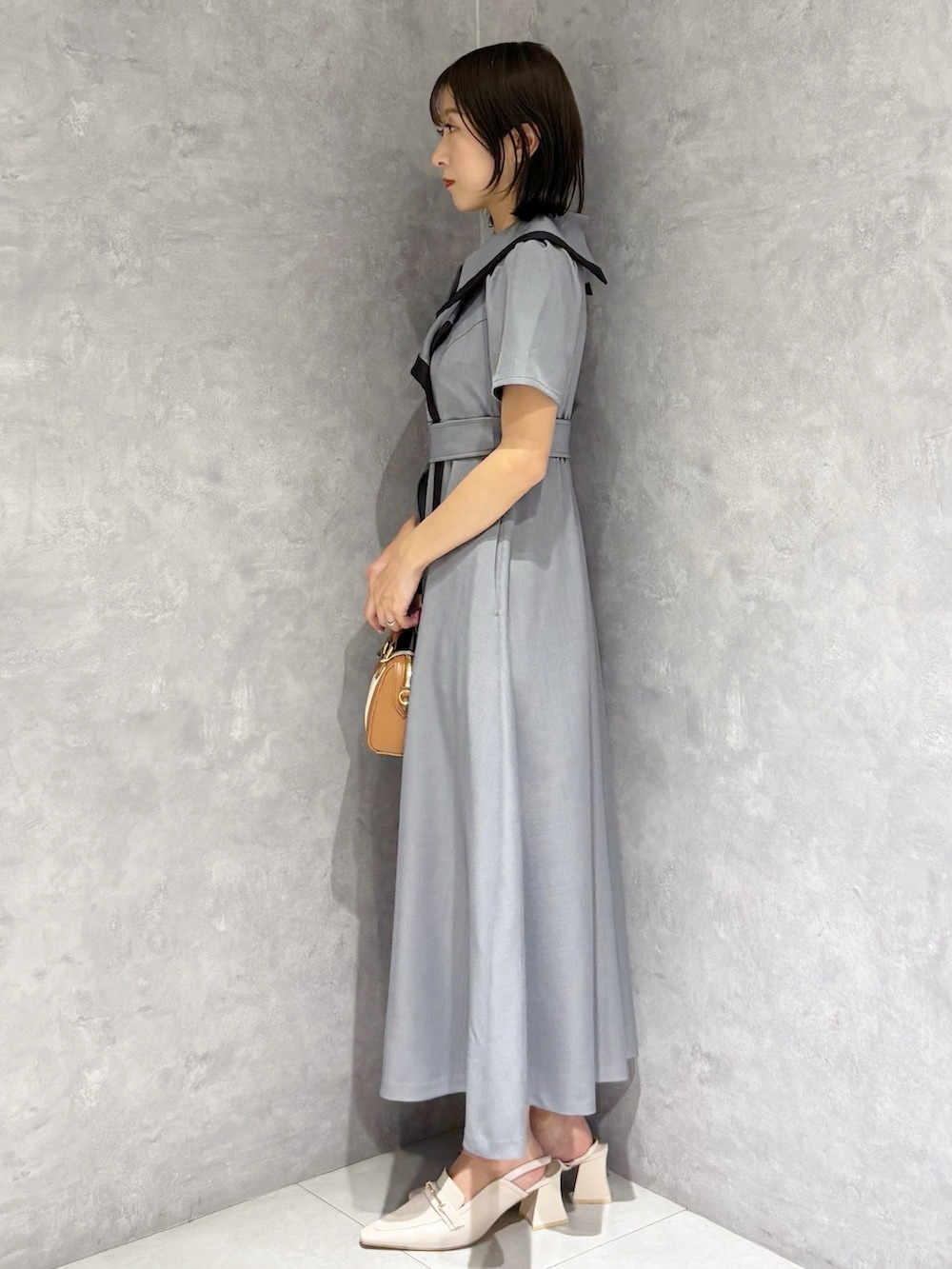 グレー系のワンピース、ホワイト系のパンプスを着用したレディースの春コーディネートの2枚目の写真