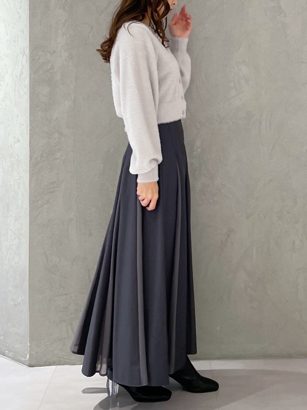 グレー系のカーディガン/ボレロ、グレー系のスカート、ブラック系のブーツを着用したレディースの冬コーディネートの5枚目の写真