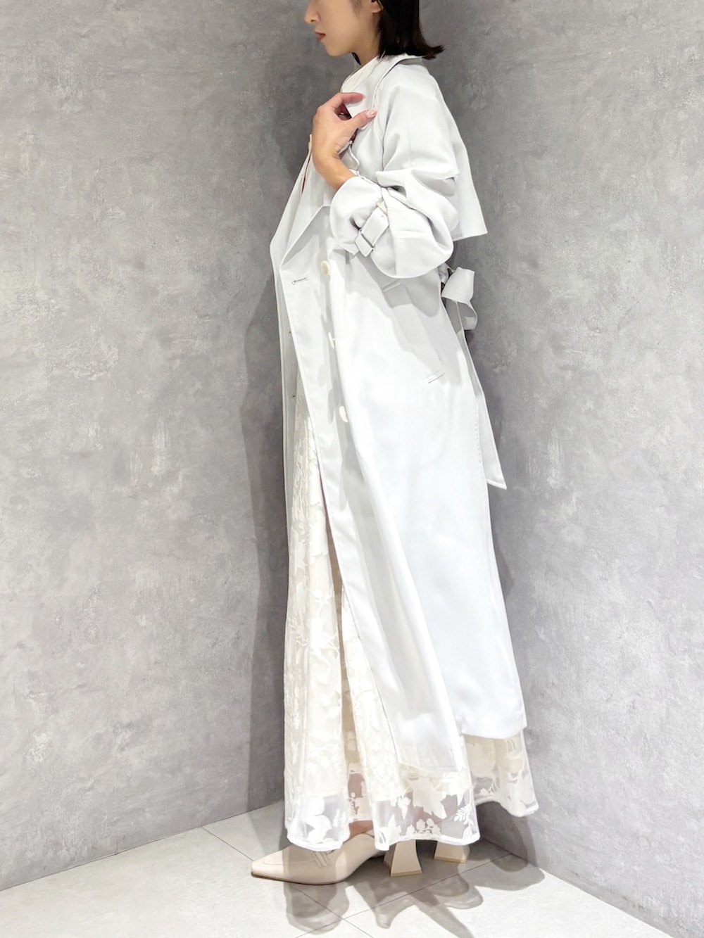 ブルー系のトレンチコート、ベージュ系のワンピース、ブラウン系のハンドバッグを着用したレディースの春コーディネートの3枚目の写真