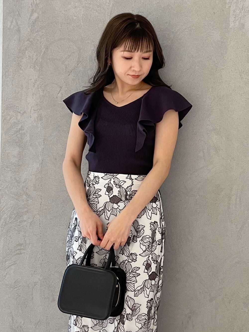 ブラック系のハンドバッグ、ブラック系のサンダル、グレー系のニット/セーターを着用したレディースの春コーディネートの2枚目の写真