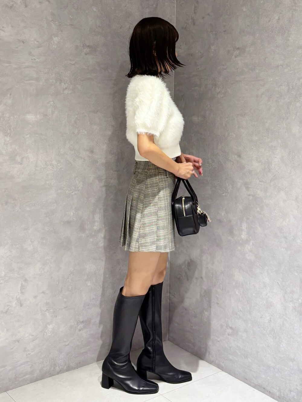 グレー系のスカート、ホワイト系のニット/セーター、ブラック系のブーツを着用したレディースの夏コーディネートの5枚目の写真