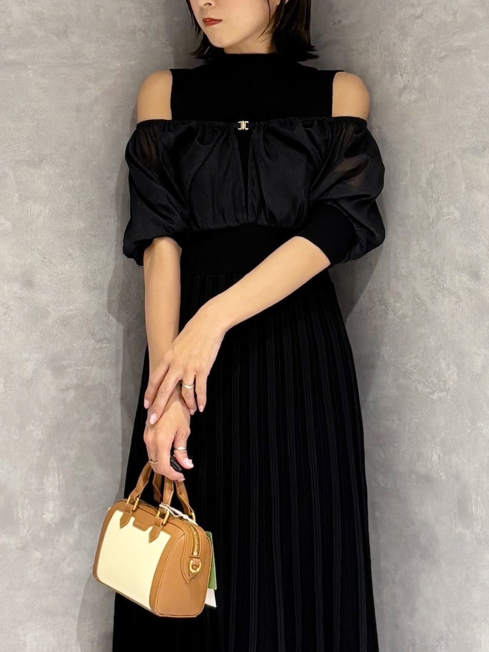 ブラウン系のハンドバッグ、ブラック系のワンピースを着用したレディースの春コーディネートの5枚目の写真
