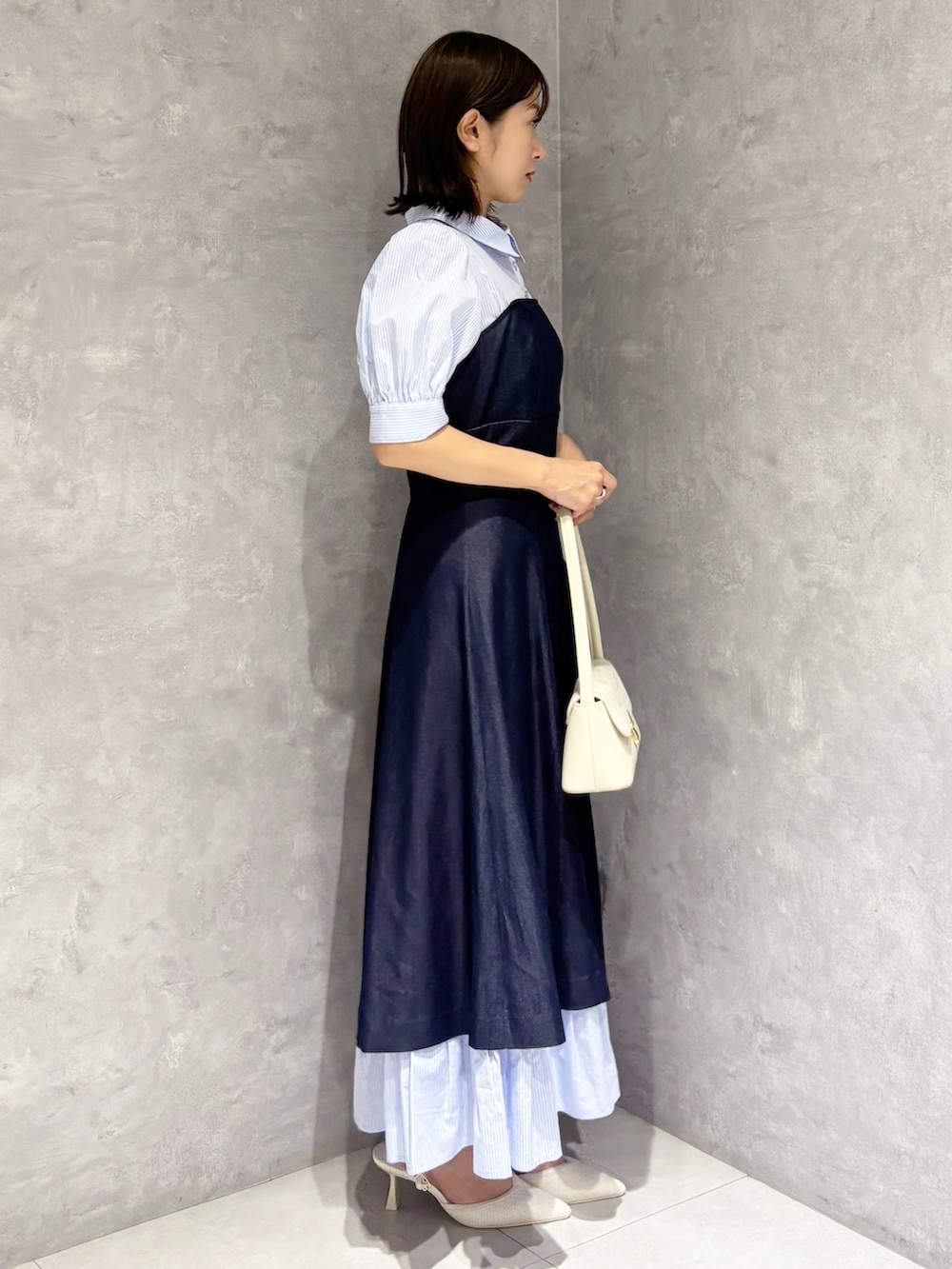 ブルー系のワンピース、ホワイト系のパンプス、ホワイト系のハンドバッグを着用したレディースの春コーディネートの4枚目の写真