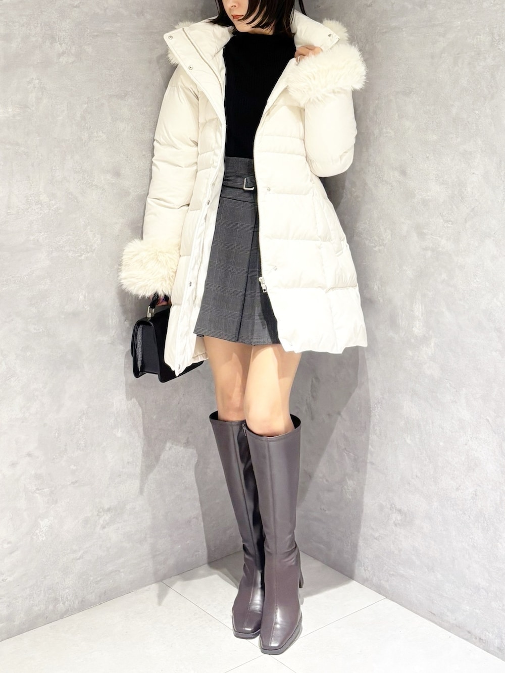 グレー系のスカート、ブラック系のニット/セーター、ホワイト系のダウンジャケット/コートを着用したレディースの冬コーディネートの5枚目の写真