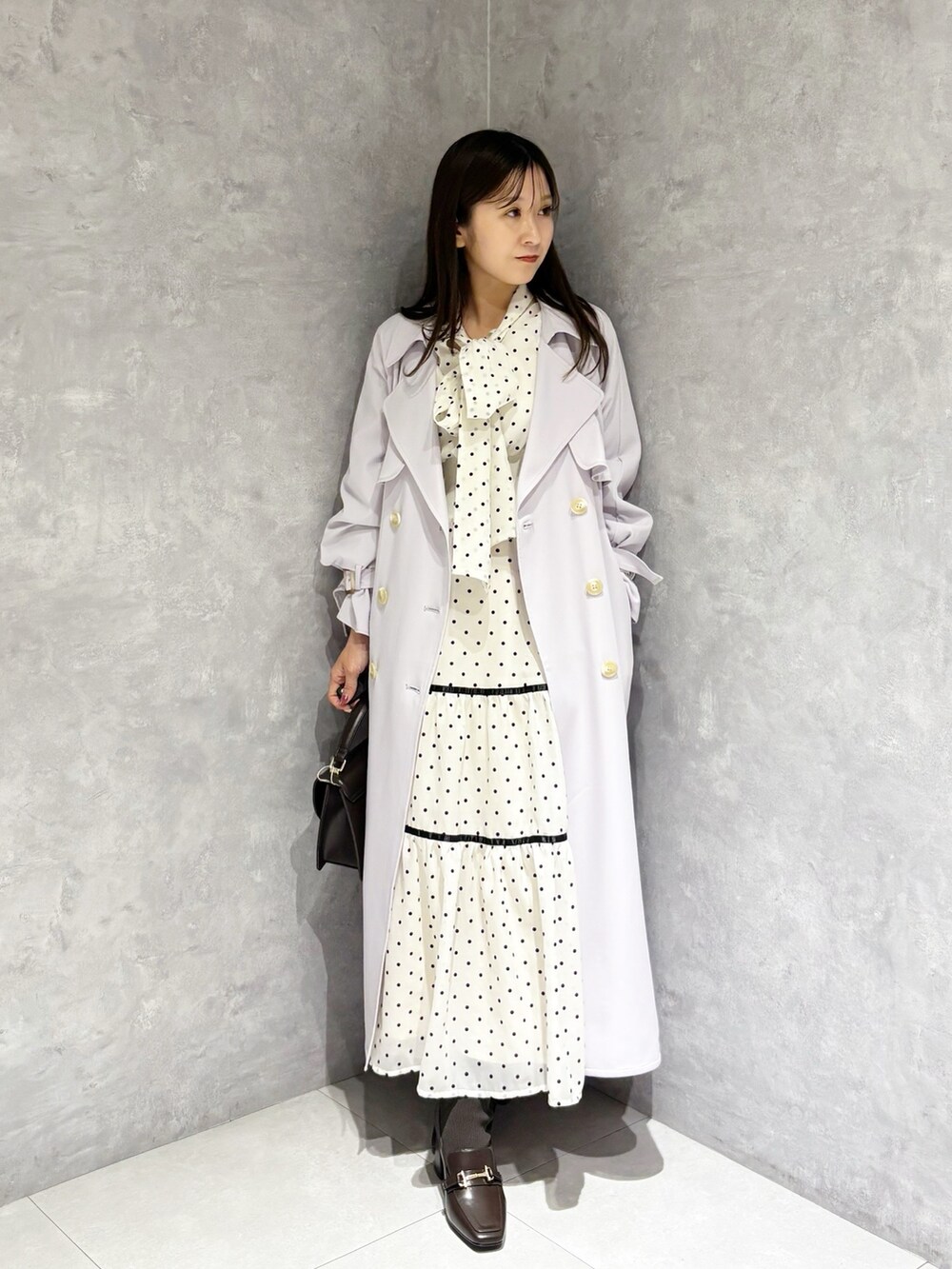 ホワイト系のワンピース、パープル系のトレンチコート、ブラウン系のハンドバッグを着用したレディースの冬コーディネートの8枚目の写真