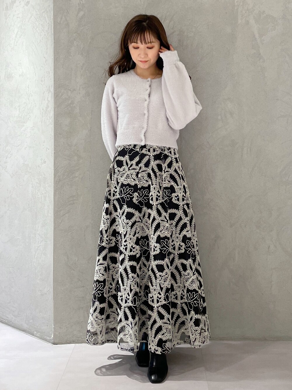 ブラック系のスカート、グレー系のカーディガン/ボレロ、ブラック系のブーツを着用したレディースの冬コーディネートの4枚目の写真