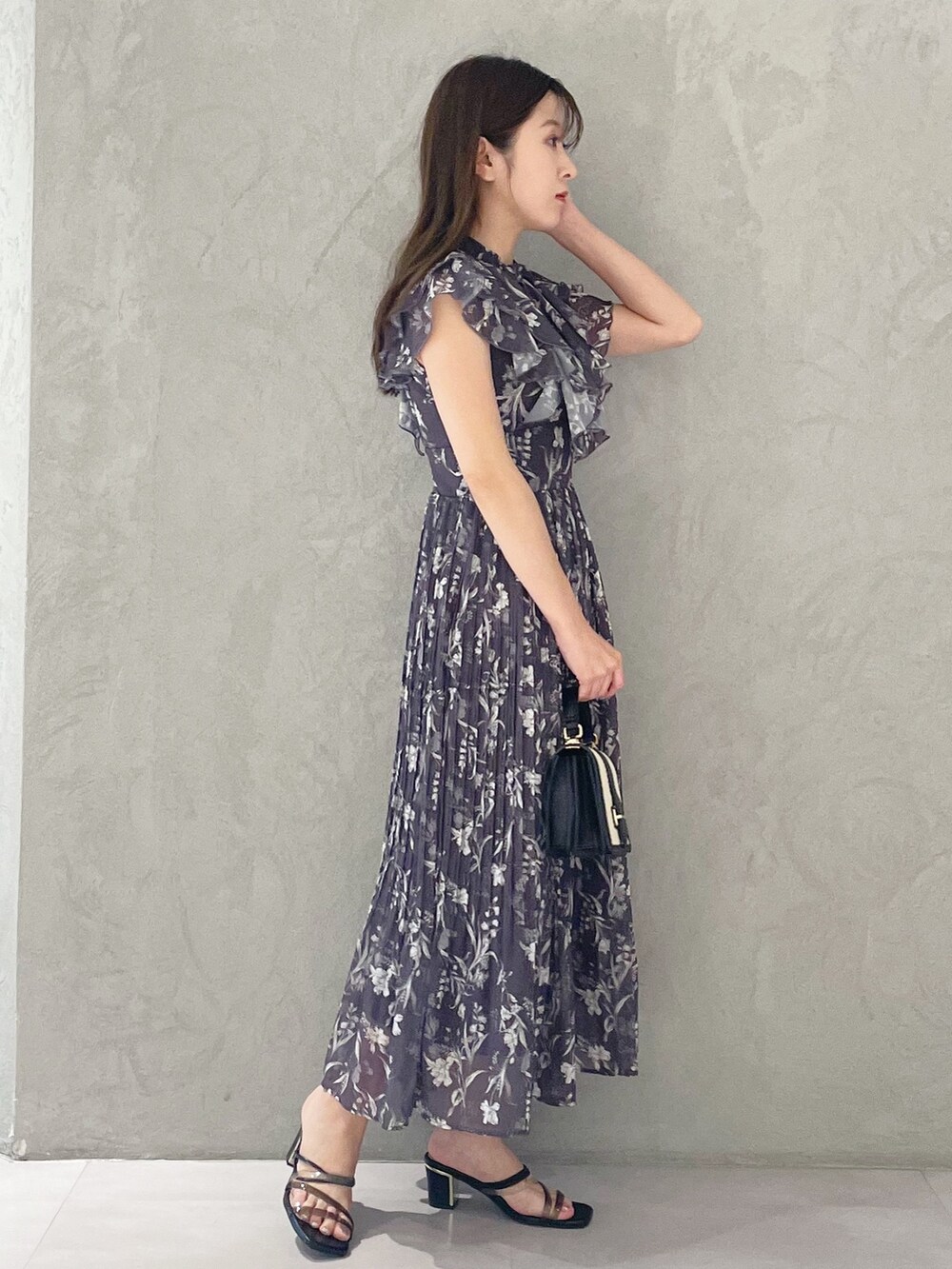 ブラック系のハンドバッグ、ブラック系のサンダル、グレー系のワンピースを着用したレディースの春コーディネートの2枚目の写真