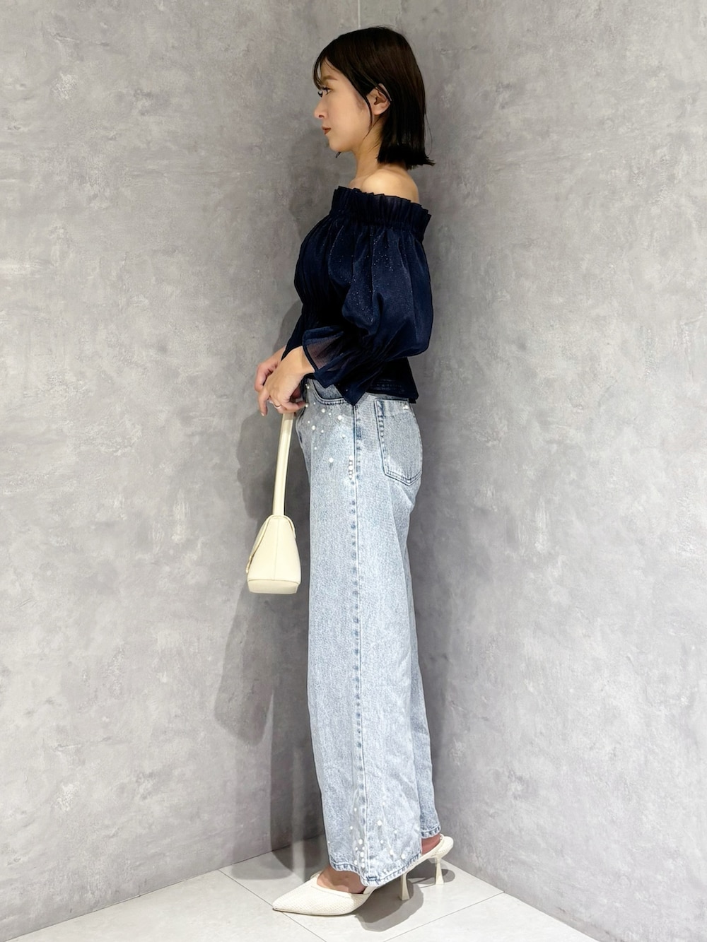 ブルー系のデニムパンツ、ブルー系のシャツ/ブラウス、ホワイト系のハンドバッグを着用したレディースの春コーディネートの4枚目の写真