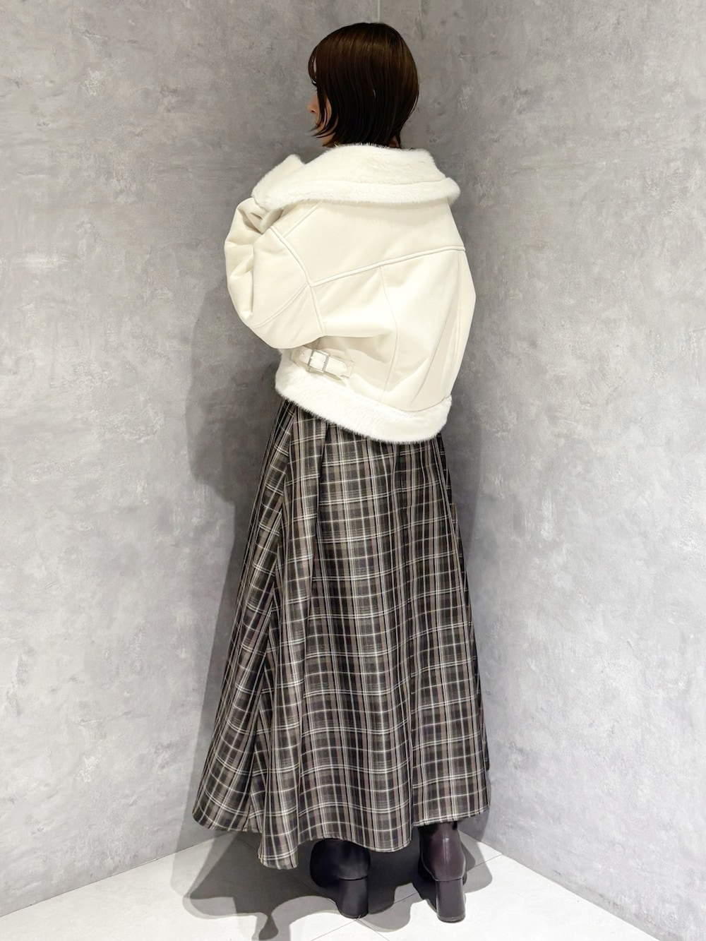 ブラック系のニット/セーター、ホワイト系のムートンコート、ブラック系のハンドバッグを着用したレディースの冬コーディネートの3枚目の写真