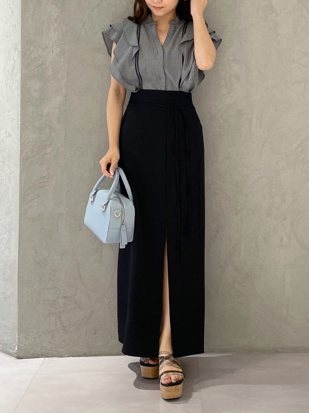 ブラック系のスカート、ブラック系のサンダル、ブルー系のボストンバッグを着用したレディースの春コーディネートの7枚目の写真