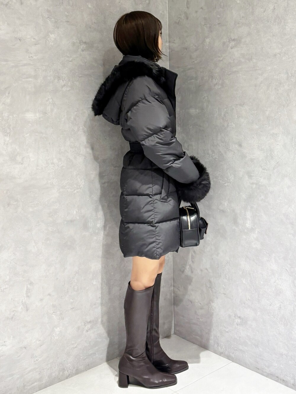 ブラウン系のブーツ、ブラック系のハンドバッグ、ブラック系のニット/セーターを着用したレディースの秋コーディネートの3枚目の写真