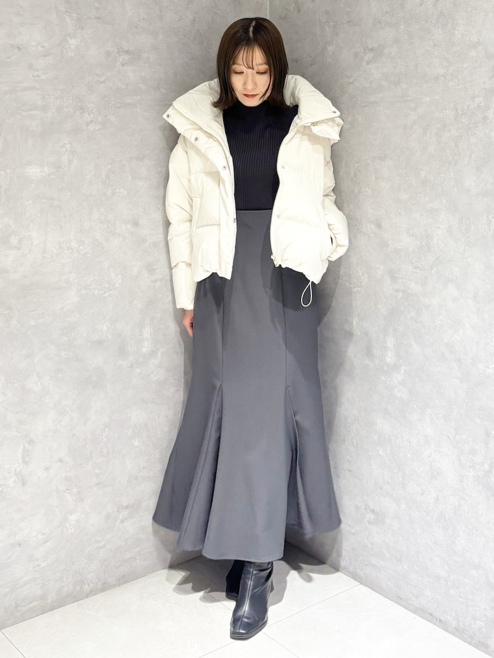 グレー系のスカート、グレー系のニット/セーター、ホワイト系のダウンジャケット/コートを着用したレディースの冬コーディネートの5枚目の写真