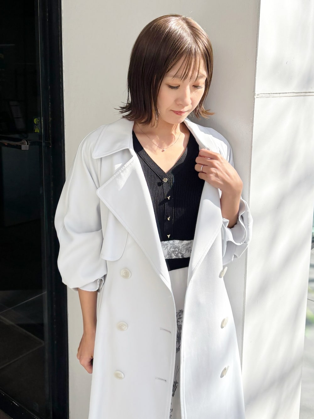 ブラック系のワンピース、ブラウン系のパンプス、ブルー系のトレンチコートを着用したレディースの春コーディネートの3枚目の写真