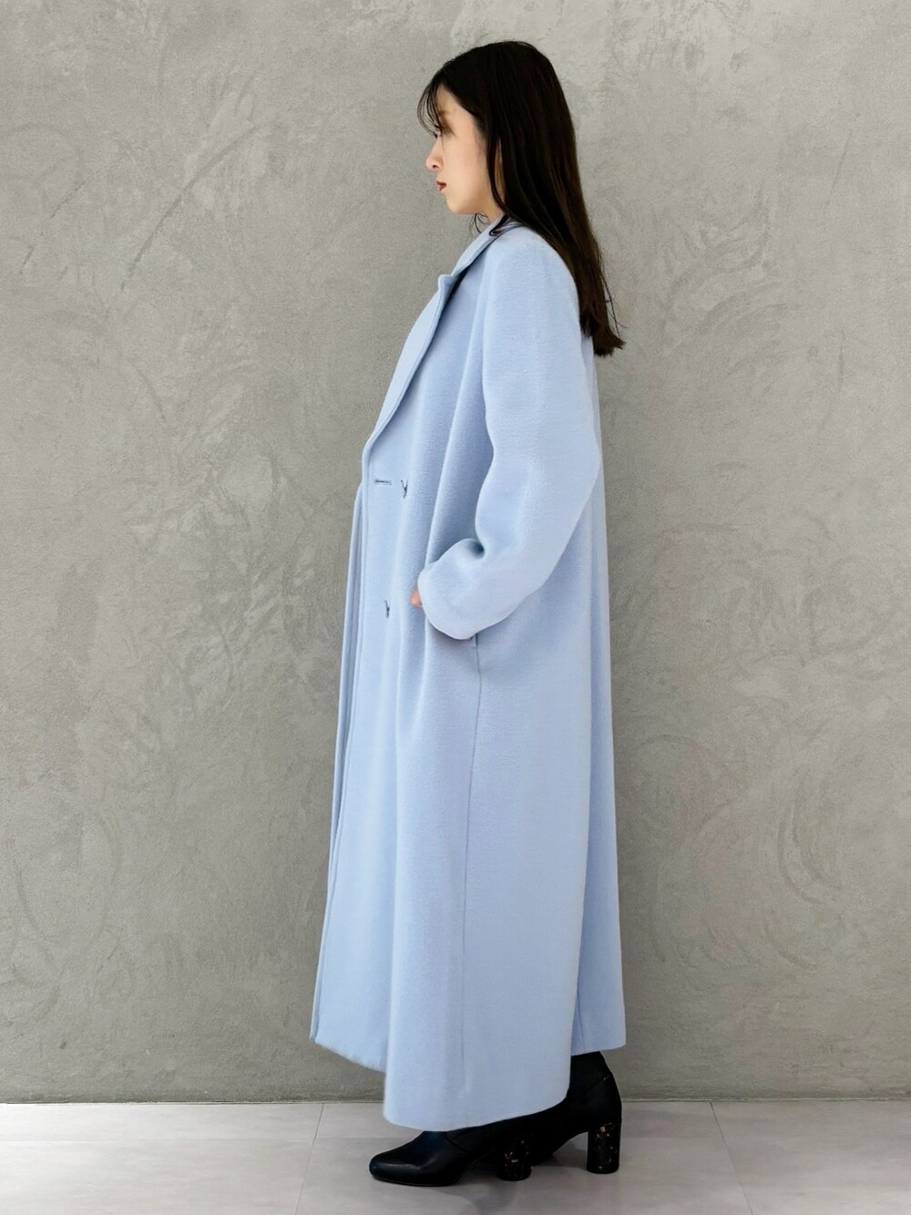 ブルー系のチェスターコート、ブラック系のブーツ、ホワイト系のワンピースを着用したレディースの冬コーディネートの5枚目の写真