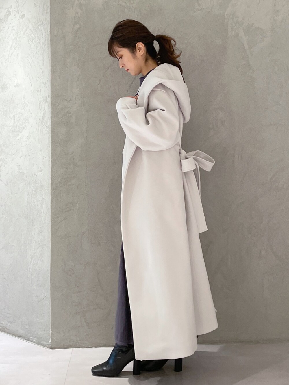 ホワイト系のチェスターコート、ブラック系のブーツ、ブルー系のワンピースを着用したレディースの秋コーディネートの4枚目の写真