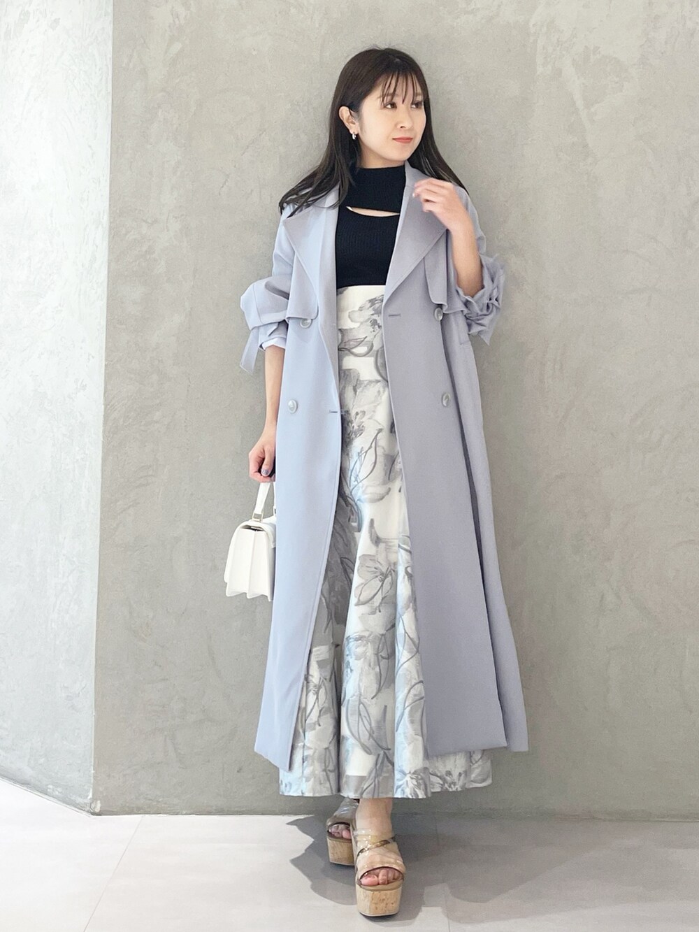 ブルー系のトレンチコート、ブラウン系のサンダル、ホワイト系のショルダーバッグを着用したレディースの春コーディネートの3枚目の写真