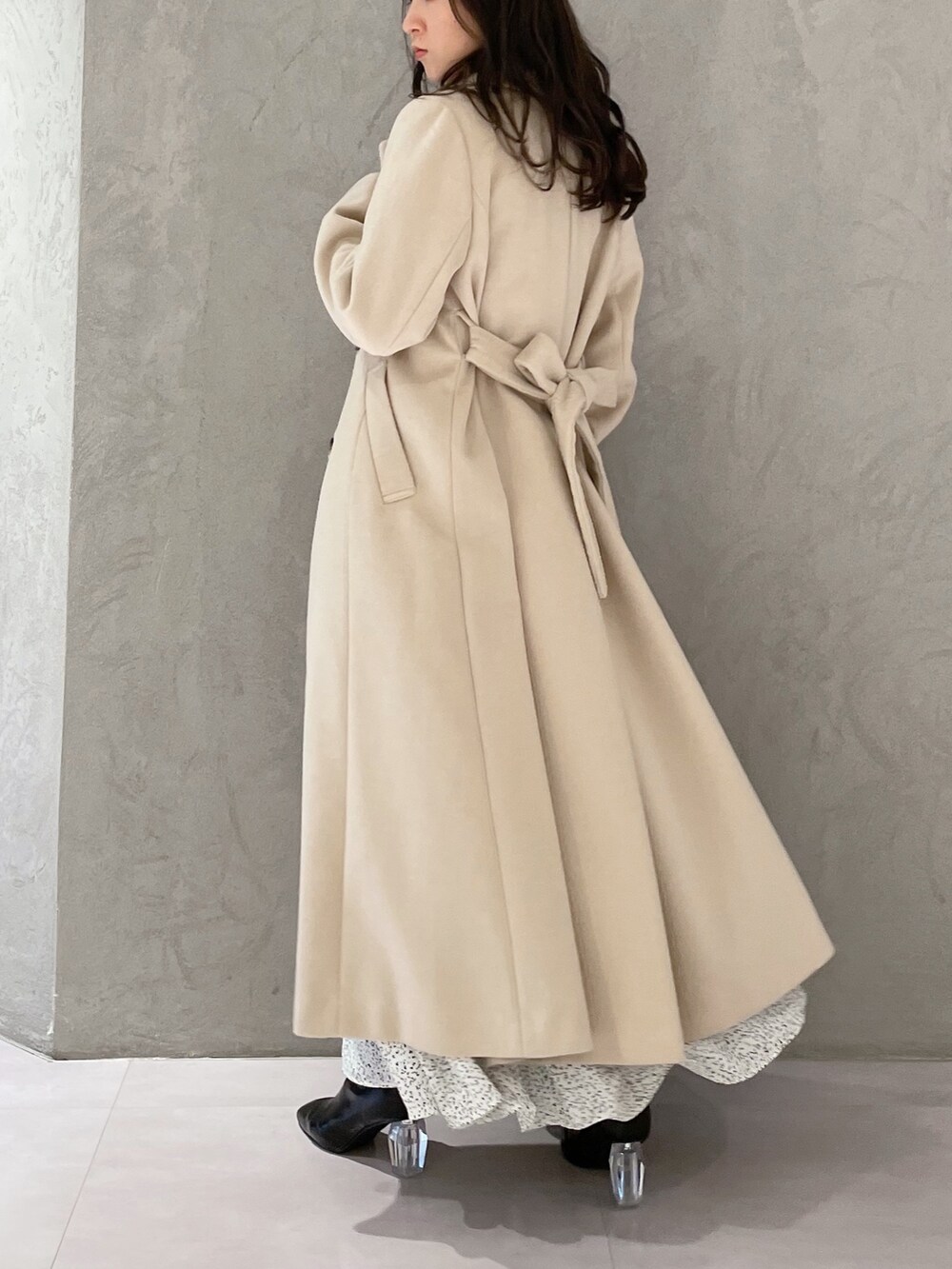 ホワイト系のワンピース、ベージュ系のチェスターコート、ブラック系のブーツを着用したレディースの秋コーディネートの5枚目の写真