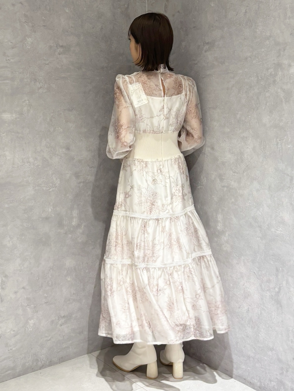 ベージュ系のショルダーバッグ、ホワイト系のブーツ、ベージュ系のワンピースを着用したレディースの冬コーディネートの3枚目の写真