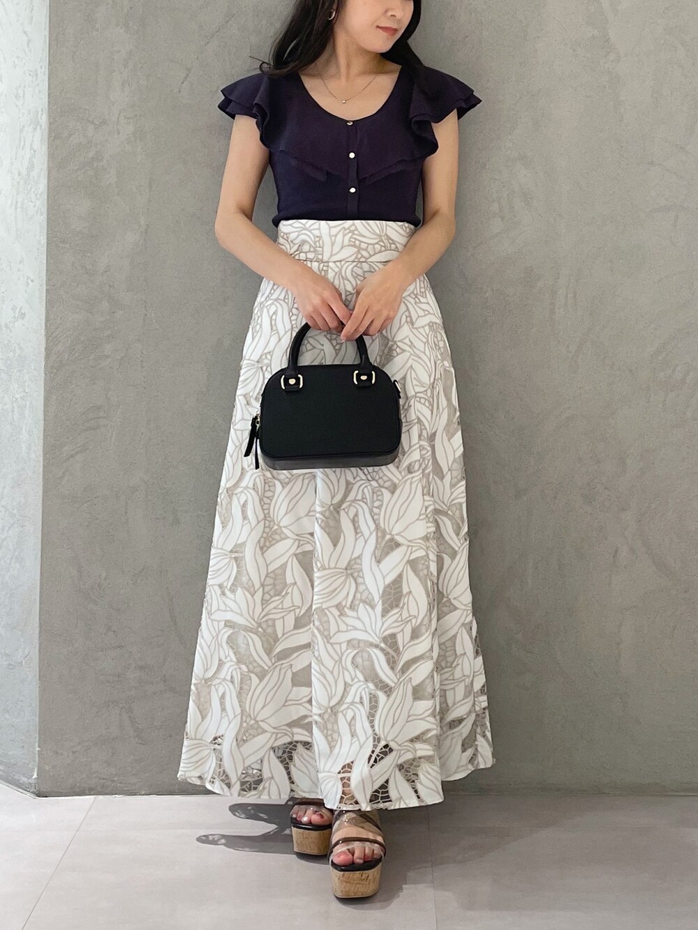 ブラック系のサンダル、ブラック系のボストンバッグ、ホワイト系のスカートを着用したレディースの春コーディネートの5枚目の写真
