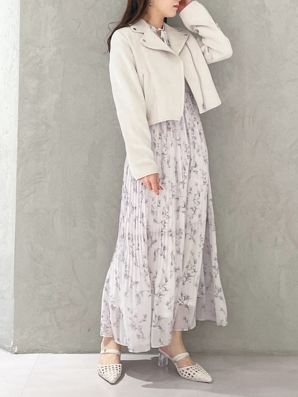 ピンク系のワンピース、ホワイト系のパンプス、ホワイト系のライダースジャケットを着用したレディースの春コーディネートの2枚目の写真