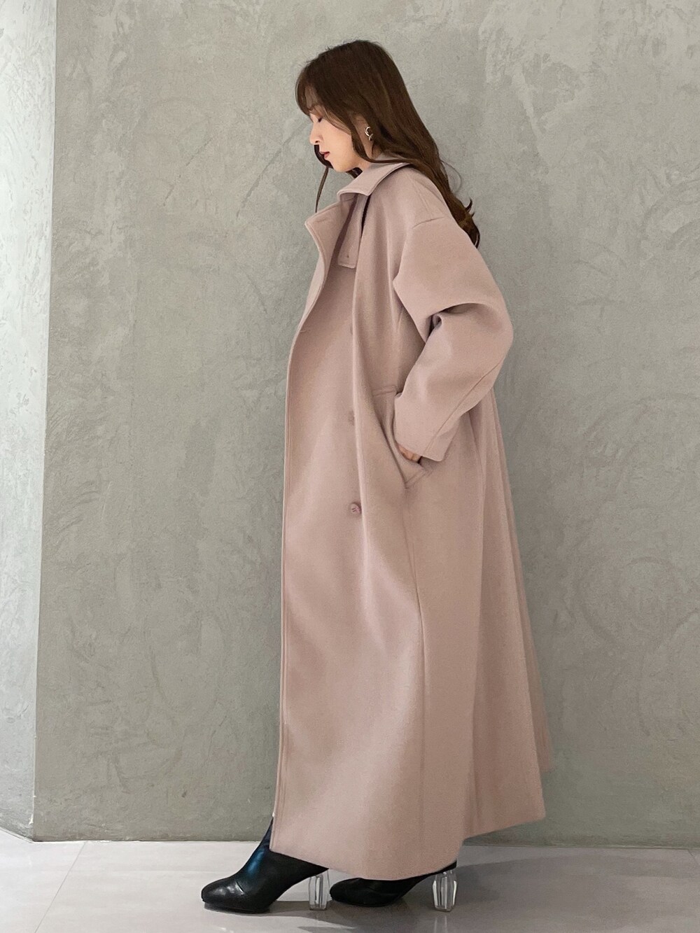 ホワイト系のワンピース、ベージュ系のステンカラーコート、ブラック系のブーツを着用したレディースの冬コーディネートの3枚目の写真