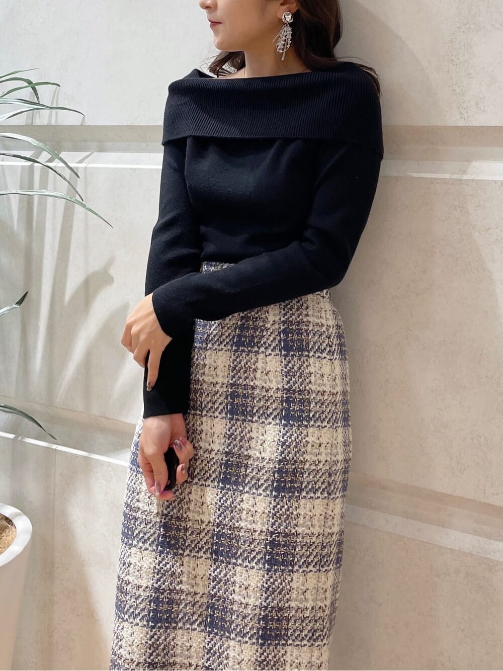 グリーン系のハンドバッグ、ブラック系のニット/セーター、ブルー系のスカートを着用したレディースの冬コーディネートの2枚目の写真